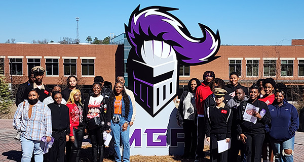 high school students posing my large duke the knight head outside macon campus library